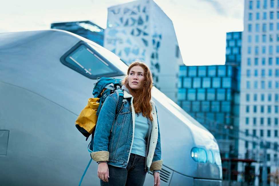 Person med ryggsekk på perongen ved siden av et tog